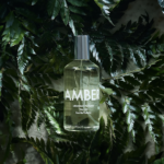 En flaske Laboratory Parfums Atlas Eau de Toilette 100 ml. (unisex) omgivet af grønne blade.