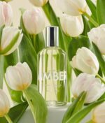 en flaske parfume, der sidder ved siden af et bundt blomster.