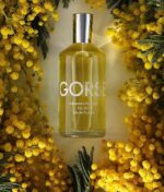 en flaske parfume omgivet af gule blomster.