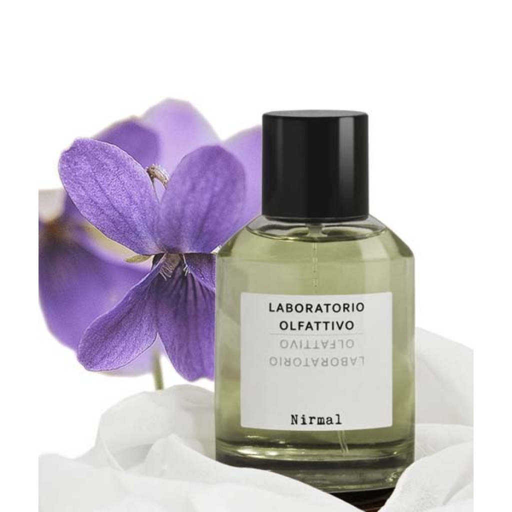 en flaske parfume, der sidder ved siden af en lilla blomst.