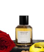 en flaske parfume ved siden af en blomst.