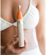 En person i en hvid bikini holder en Soleil Toujours Mineral Ally Eye Glow + Illuminator SPF 30 ml med en orange hætte.