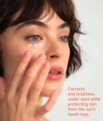 En person påfører Soleil Toujours Mineral Ally Eye Glow + Illuminator SPF 30 ml under øjnene. Teksten på billedet lyder: "Korrigerer og lysner under øjnene, mens den beskytter huden mod solens barske stråler.