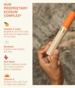 En hånd holder et Soleil Toujours Mineral Ally Eye Glow + Illuminator SPF 30 ml produkt med en orange hætte. Teksten til venstre viser ingredienser: C-vitaminester, Bisabolol, Rødalger og E-vitamin, der fremhæver deres fordele for hudpleje.