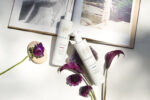 To flasker Innersense I Create Volume - Volumizing Lotion 295ml og en bog på et bord.