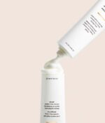 En tube med Innersense Hydrating Hair Mask - Repair & Revitalize 177ml med hætten fjernet, og dispenserer en klat af produktet. Røret er hvidt med sort tekst.
