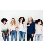 Fem kvinder med forskellige hårteksturer og -typer står på rad og række mod en hvid baggrund og bevæger legende deres hoveder og hår. De bærer afslappede toppe og jeans, der viser den ubesværede stil opnået med Innersense I Create Finish - Shine Spray 295ml.