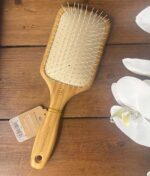 An Olivia Garden – Ionic Bambus Touch hårbørste - Detangle Nylon L - Padlebørste på et træbord.