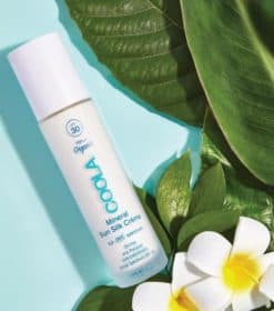 et nærbillede af en flaske deodorant ved siden af en blomst.