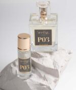 To parfumeflasker mærket "Ærlig P03 - Eau de Parfum 100 ml glasflaske" er placeret på hvide sten. Den ene flaske er større med en firkantet form, og den anden er mindre og cylindrisk. Begge har guldhætter.