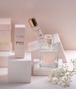 Udstilling af Ærlig P01 - Eau de Parfum 100 ml glasflaske, med sprayflaske, rulleflaske og emballagekasser, med en kvist hvide blomster.