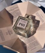 En klar firkantet flaske "Ærlig P01 - Eau de Parfum 100 ml glasflaske" vises på et åbent papir med trykt tekst i et godt oplyst miljø.