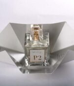 En glasflaske Ærlig P02 - Eau de Parfum 100 ml glasflaske mærket "P2" er centreret på en udfoldet sølvpapemballage med en almindelig baggrund.
