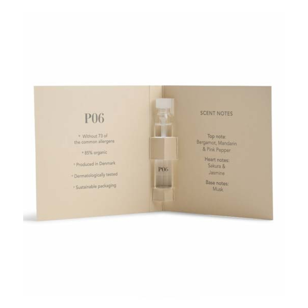 Et åbent hæfte med et lille parfumehætteglas mærket "P06" og duftnoter, herunder bergamot, mandarin, pink peber, sakura, jasmin og moskus. Tekst noterer produktets fordele og bæredygtig emballage fra **Ærlig Duftprøver - P01, P02, P03, P04, P05 & P06 6 x 1,3 ml**.