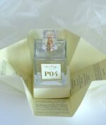 En klar glasflaske "Ærlig P04 Eau de Parfum 100 ml glasflaske" med en firkantet, gennemsigtig hætte vises på et udfoldet instruktionsark med tekst.
