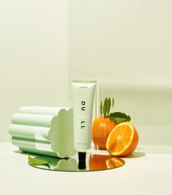 et hvidt bord med appelsiner og en tube lotion.