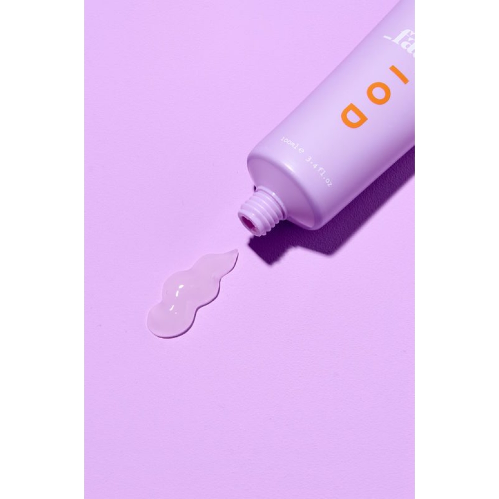 en tube lotion, der sidder oven på en lyserød overflade.