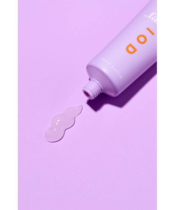 en tube lotion, der sidder oven på en lyserød overflade.