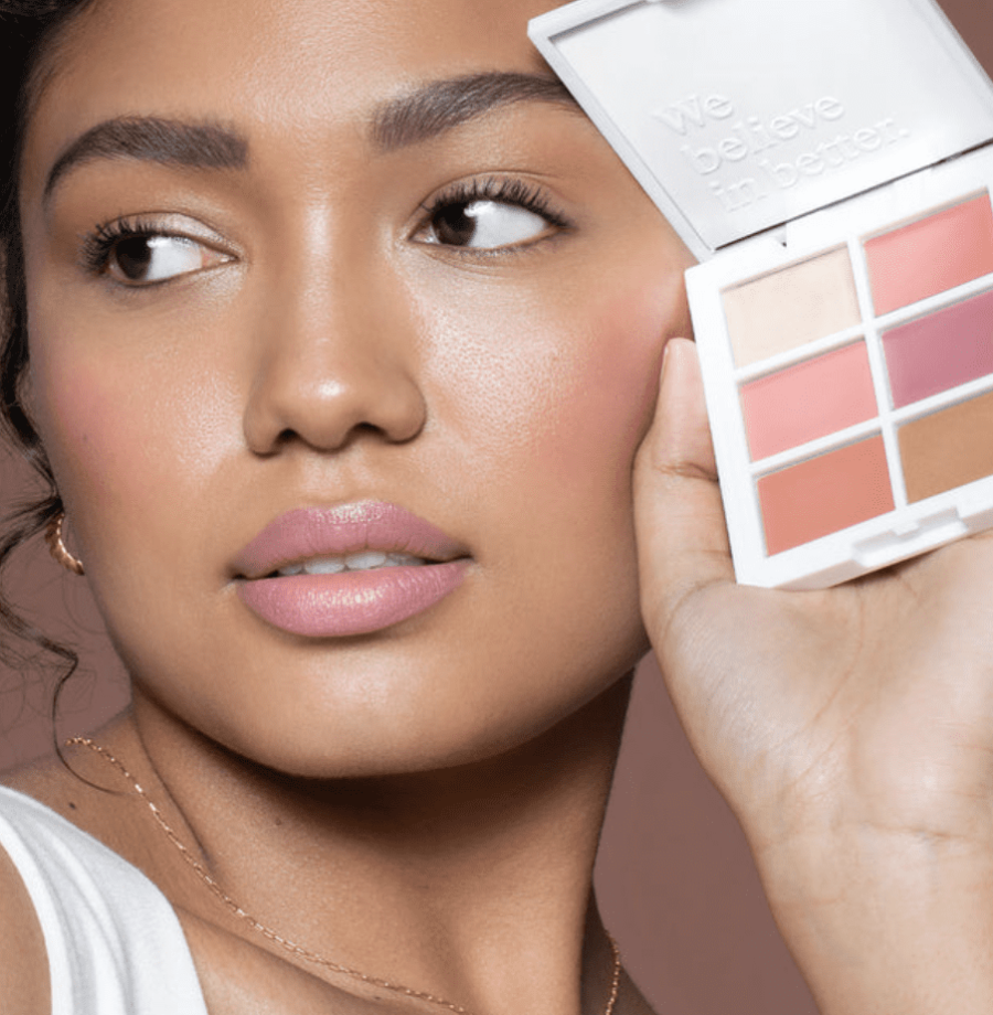 en kvinde, der holder en lyserød og hvid makeup-palette op.
