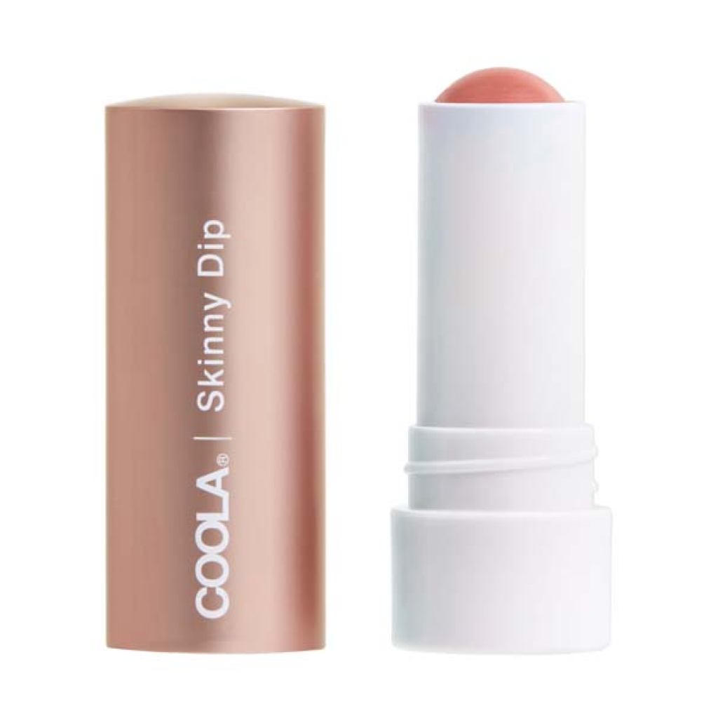 En tube COOLA Mineral Liplux® Tinted Lip Balm SPF 30 - Skinny Dip med en åben roseguldhætte, der afslører en koralfarvet balsamstick inde i en hvid base.