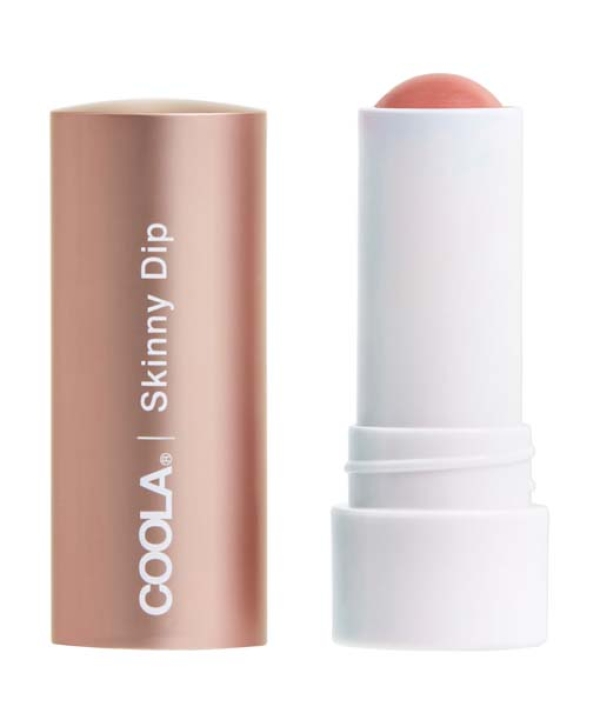 En tube COOLA Mineral Liplux® Tinted Lip Balm SPF 30 - Skinny Dip med en åben roseguldhætte, der afslører en koralfarvet balsamstick inde i en hvid base.