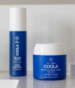 To COOLA hudplejeprodukter i blå beholdere: et serum til venstre og en COOLA Refreshing Water Cream SPF 50 - 44ml til højre, begge til solbeskyttelse med SPF 50.
