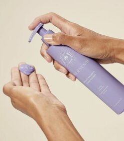 to hænder, der holder en lilla flaske lotion.