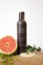 en flaske john masters naturals grapefrugt shampoo ved siden af en drue.