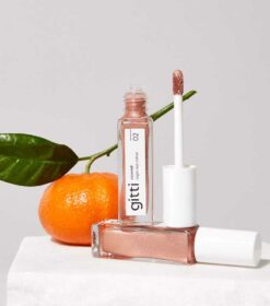 en flaske lipglosser ved siden af en appelsin.