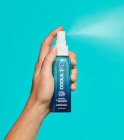 en hånd, der holder en flaske deodorant på en blå baggrund.
