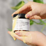 en persons hånd, der holder en krukke med Evolve Organic Beauty Enzyme + Vitamin C Cleansing Powder 70 g creme.