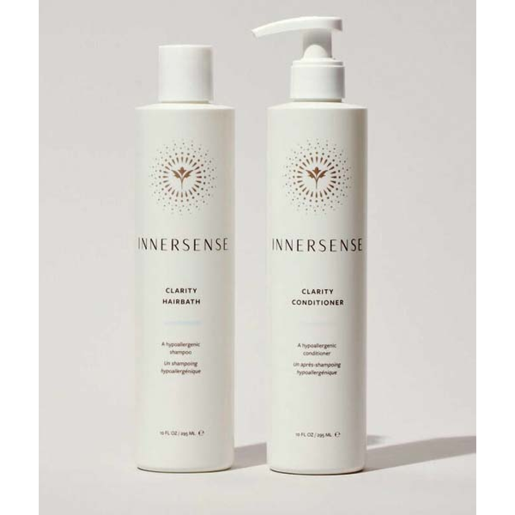 To hvide flasker med Innersense hårplejeprodukter vises: den ene mærket "Clarity Hairbath" og den anden "Clarity Conditioner", begge med et minimalistisk design. Sammen danner de Innersense Clear + Calm Clarity Duo - Hairbath & Conditioner for en rolig hårplejeoplevelse.