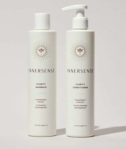 To hvide flasker med Innersense hårplejeprodukter vises: den ene mærket "Clarity Hairbath" og den anden "Clarity Conditioner", begge med et minimalistisk design. Sammen danner de Innersense Clear + Calm Clarity Duo - Hairbath & Conditioner for en rolig hårplejeoplevelse.