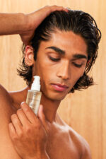 En mand uden hår reder sit hår med Innersense Hair Renew Scalp Oil 29 ml.