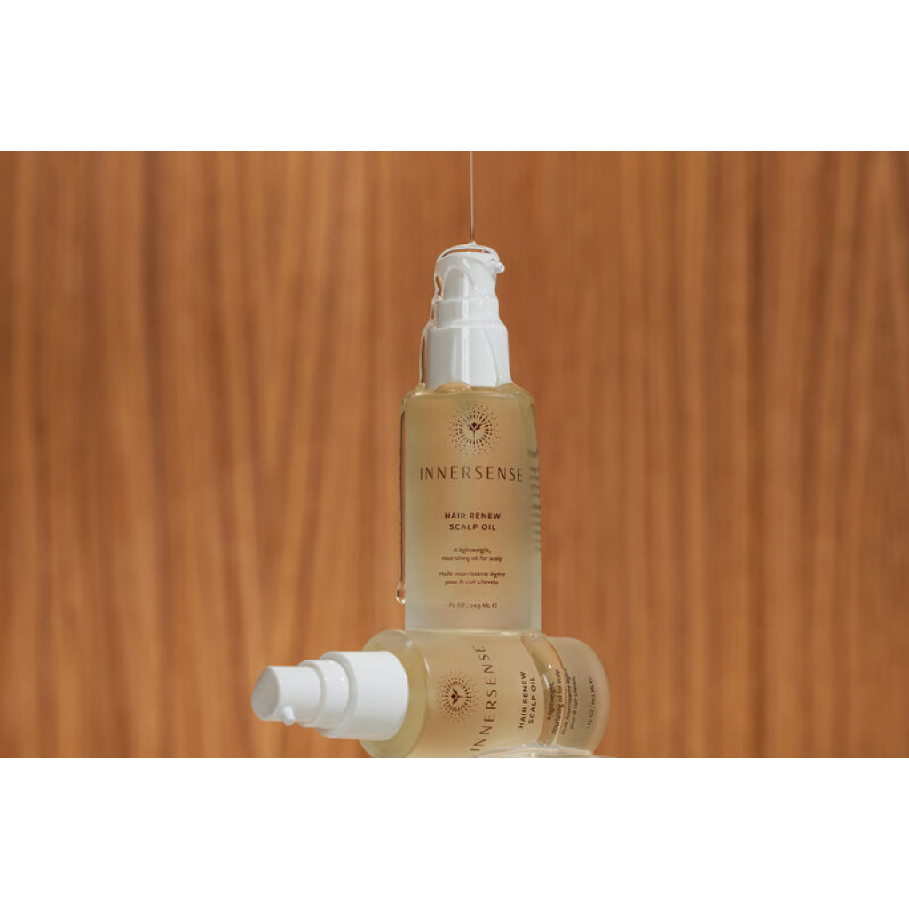 En flaske Innersense Hair Renew Scalp Oil 29 ml siddende oven på en træoverflade.