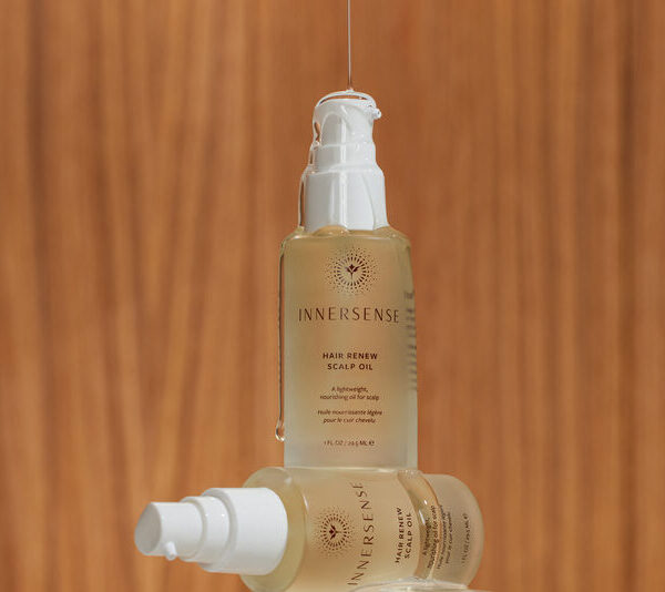 En flaske Innersense Hair Renew Scalp Oil 29 ml siddende oven på en træoverflade.