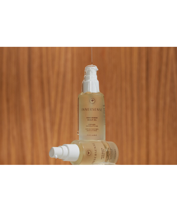 En flaske Innersense Hair Renew Scalp Oil 29 ml siddende oven på en træoverflade.