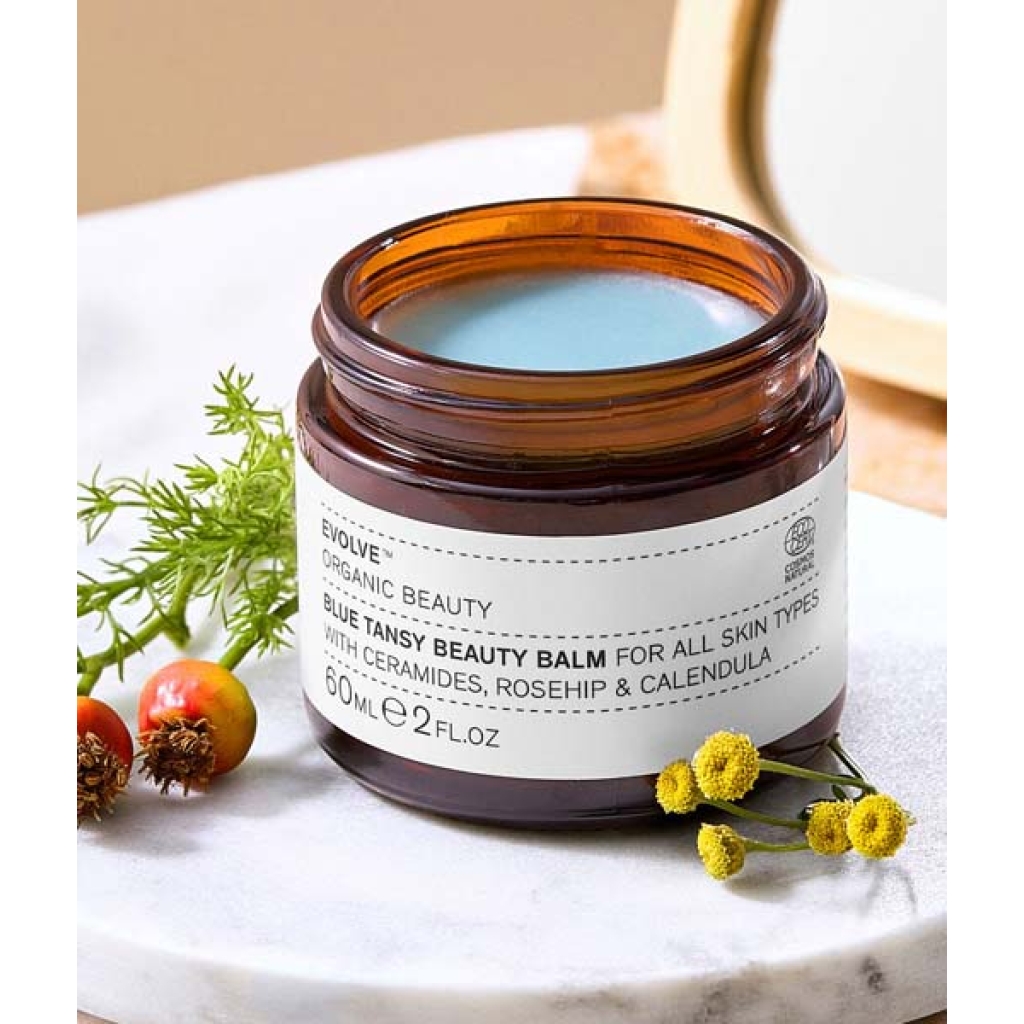 En krukke med Evolve Organic Beauty - Blue Tansy Beauty Balm 60 ml står på et marmorbord.