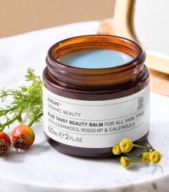 En krukke med Evolve Organic Beauty - Blue Tansy Beauty Balm 60 ml står på et marmorbord.