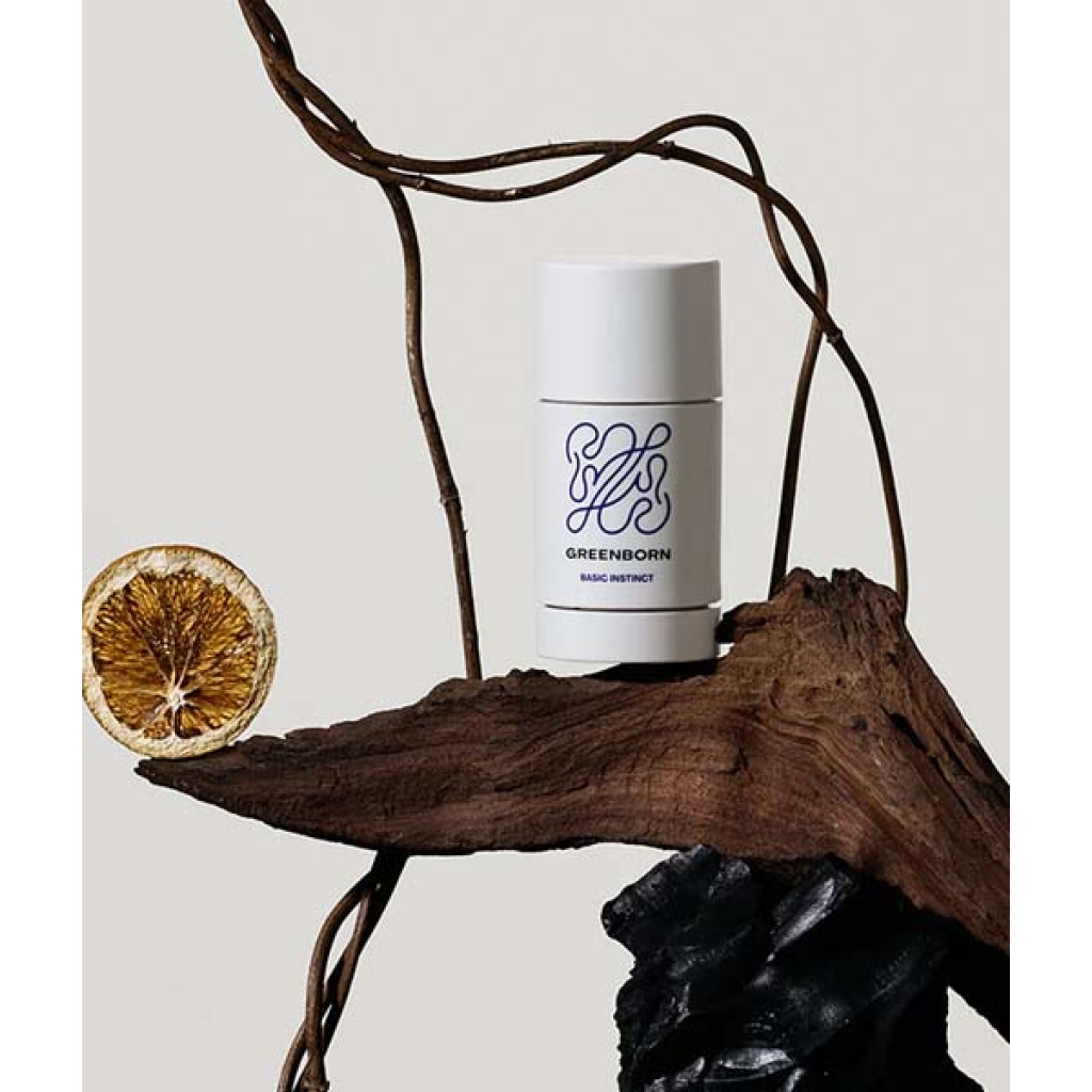 En Green Born Deo Stick Basic Instinct 50 g sidder på toppen af et stykke træ.