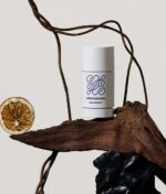 En Green Born Deo Stick Basic Instinct 50 g sidder på toppen af et stykke træ.