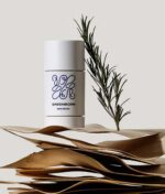 En Green Born Deo Stick New Roots 50 g siddende oven på en stak papirer.
