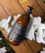 En flaske NAKED - Natural Haircare - Hårmaske nr. 1, 1000 ml siddende på et træbord.