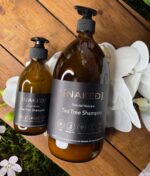 A NAKED - Natural Haircare Tea Tree Shampoo, 250 ml på et træbord.
