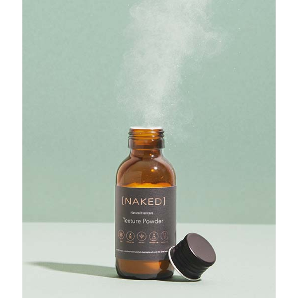 En NAKED - Natural Haircare tekstur pulver 9 g flaske farvet med en damp, der kommer ud af den.
