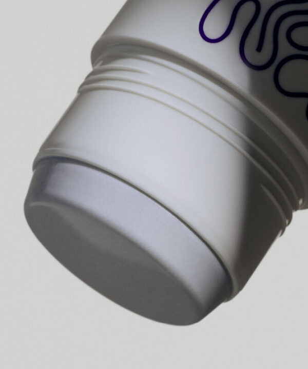 Et nærbillede af en Green Born Deo Stick Bitter Sweet 50 g med et lilla logo på.