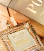 Nærbillede af en parfumeflaske af glas med en etiket med teksten "Ærlig P06 – Eau de Parfum 15 ml glasflaske Roll on TRAVEL" ved siden af dens matchende guldemballage.