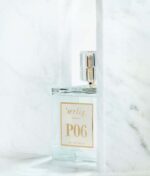 En flaske parfume mærket "Ærlig P06 – Eau de Parfum 15 ml glasflaske Roll on TRAVEL" er placeret på en hvid marmor baggrund.