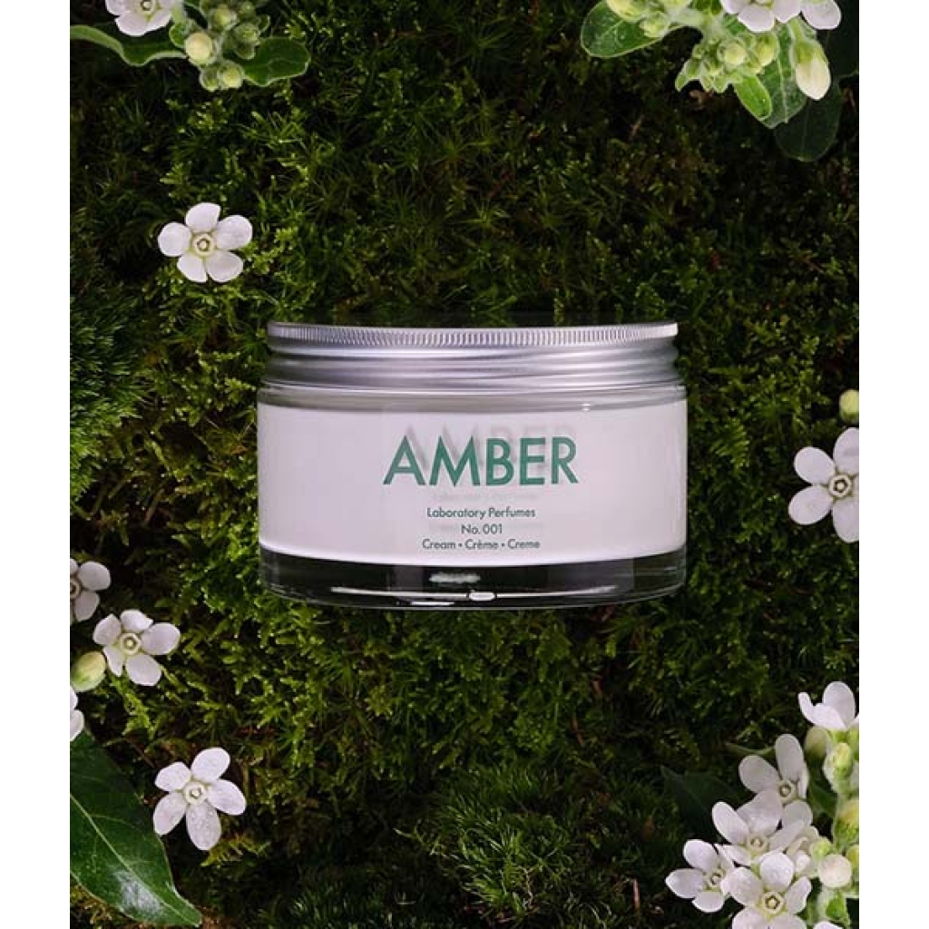 En krukke med Laboratory Parfums Amber Creme nr. 001, 200 ml omgivet af mos og blomster.