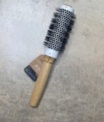 En Olivia Garden Bamboo Touch Blowout rundbørste termisk 23 mm hårbørste på betongulv.
